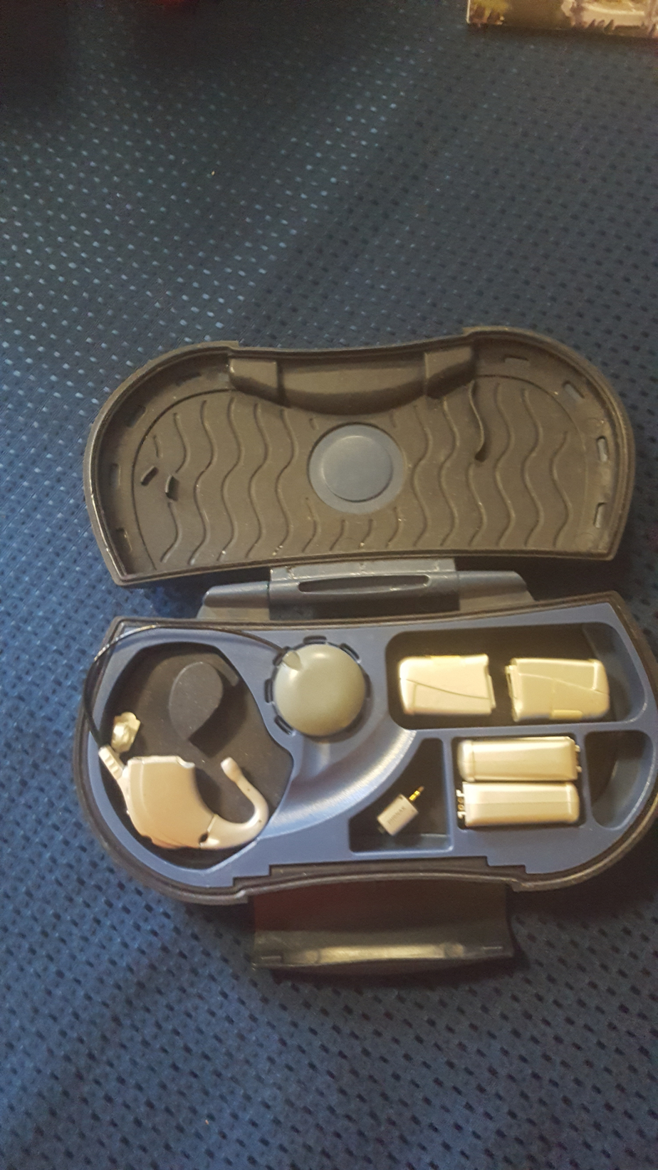 Pictured here is a box of hearing aid and a sound processor for Inef's cochlear implant. Those are the assistive devices Inef uses to help her hear better. 
